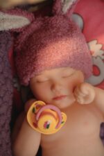 Silicone realistic reborn doll wearing a soft bunny hat, perfect for collectors and children. High-q.
