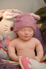 Realistic silicone reborn doll with pink bunny hat, perfect for collectors and doll enthusiasts.