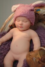 Silicone Reborn Baby Doll with pink bunny hat, lifelike features, and soft skin. Perfect for collect.