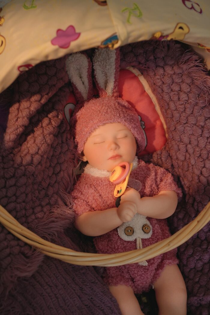Realistic silicone baby doll with bunny hat for collectors.