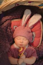 Realistic silicone reborn doll with bunny ears, soft skin, and pacifier for collectors.
