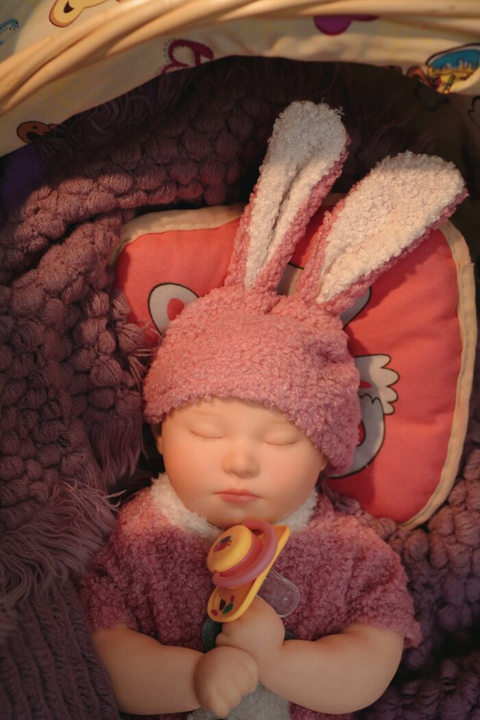 Realistic silicone reborn doll with bunny ears, soft skin, and pacifier for collectors.