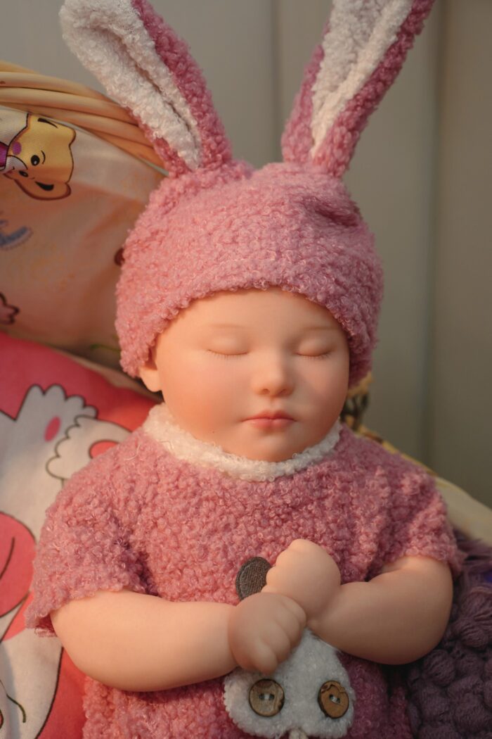 Reborn doll with bunny ears, pink fuzzy outfit, and realistic features for collectors and children.