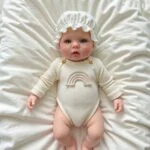 Realistic silicone reborn doll of a baby girl with rainbow-themed outfit and bonnet.