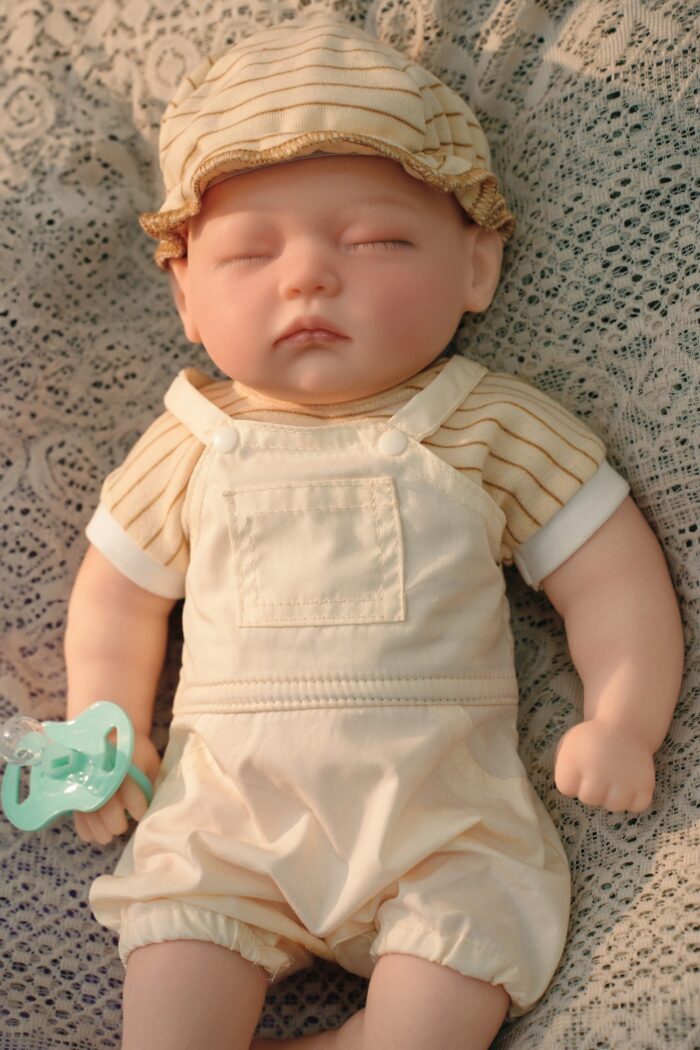Reborn panenka v béžovém oblečení s kloboukem, realistické silikonové miminko pro sběratele.