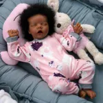 Silikonová vinylová panenka spící afroamerické dívky s zakořeněnými vlasy, realistickými rysy.