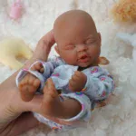 Mini afroamerická reborn panenka s realistickými rysy a měkkou silikonovou kůží.