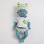 Znovuzrozená panenka z měkkého, ohebného platinového silikonu s oblečením s motivem víly a rozkošným žabím límečkem.