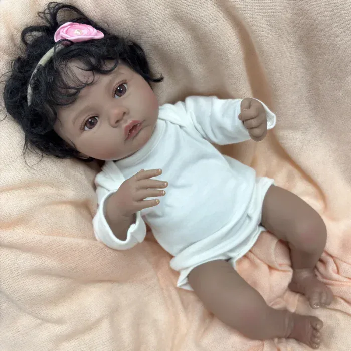 Reborn panenka Meadow s tmavou pletí, černými kudrnatými vlasy a realistickým vinylovým tělem, ideální do sbírky.
