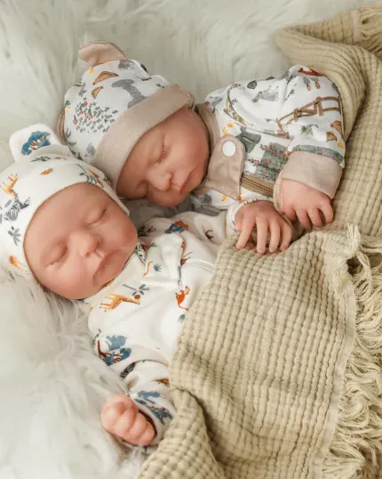 Znovuzrozená dvojčata oblečená v roztomilých oblečcích s měkkými látkovými tělíčky, ideální pro sběratele a novorozence.