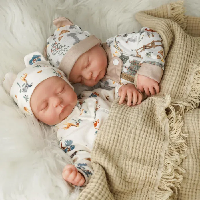 Znovuzrozená dvojčata oblečená v roztomilých oblečcích s měkkými látkovými tělíčky, ideální pro sběratele a novorozence.