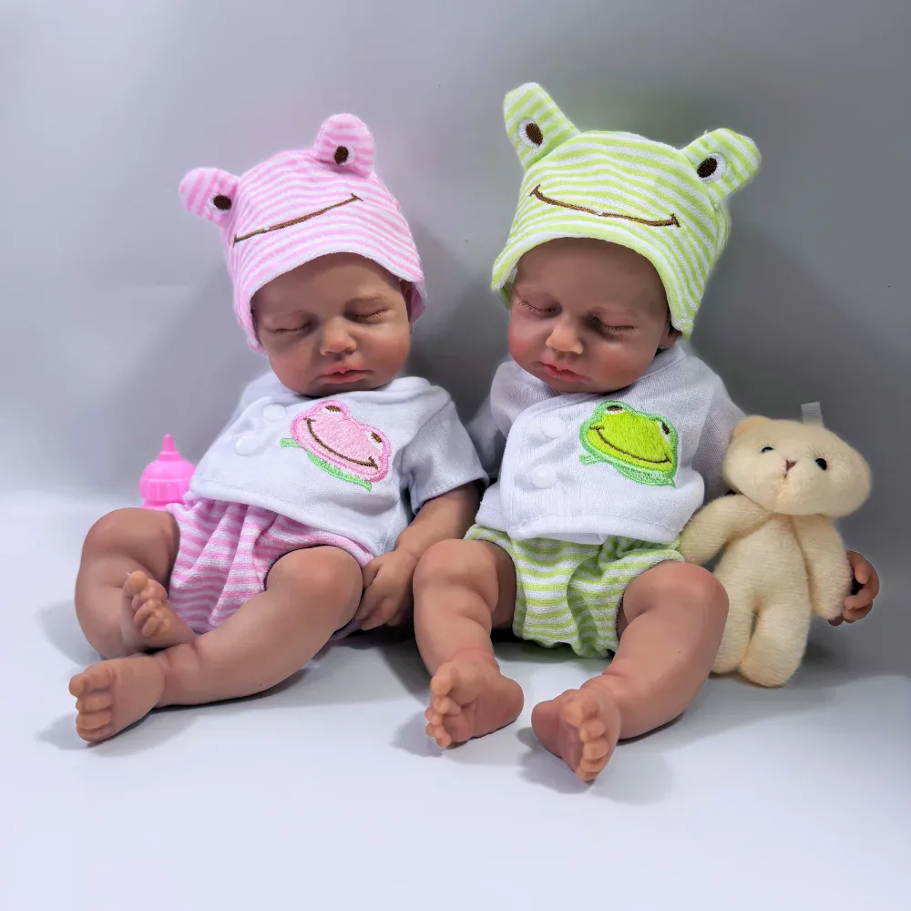 Roztomilé panenky v žabích čepicích a pyžamech, ideální jako vánoční dárky a výzdoba dětského pokoje. Rozkošné silikonové reborn panenky s kloboučky s motivem žáby, měkké a omyvatelné, ideální pro sběratele.