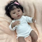Detailní silikonová reborn panenka s tmavou pletí a kudrnatými černými vlasy, ideální pro sběratele a děti.