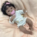 Znovuzrozená afroamerická panenka holčička s kudrnatými černými vlasy.