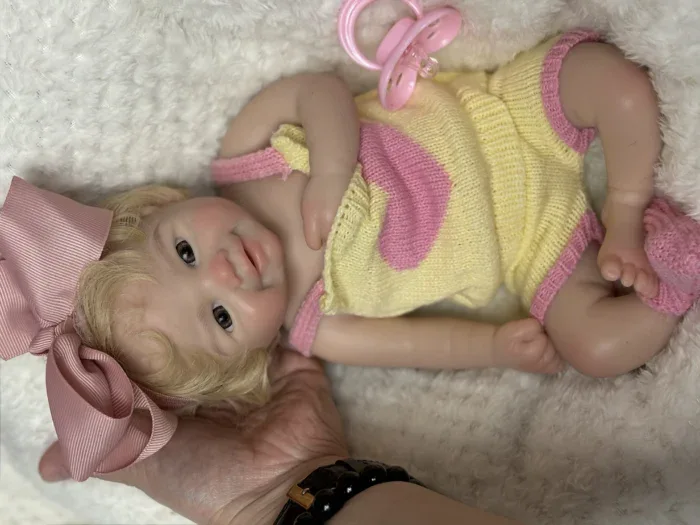 Reālistiska atdzimušas silikona meitenes lelle ar sakņotiem matiem, atvērtu muti un mazgājamām ķermeņa daļām.