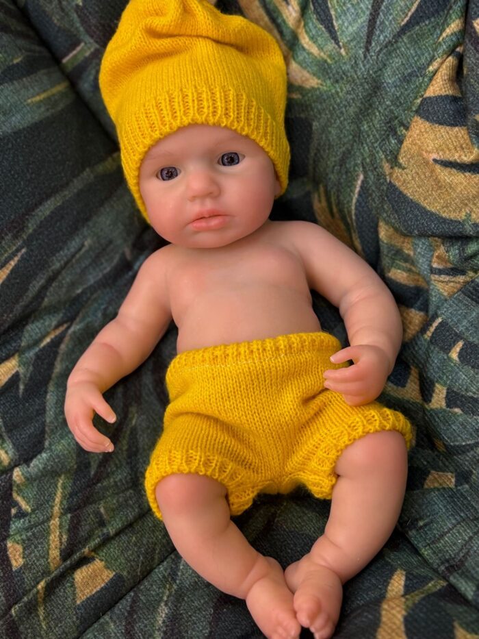 Poupée reborn en silicone de haute qualité ressemblant à un vrai bébé, vêtue d'un chapeau jaune et d'un short pour la vie.