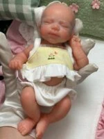 Păpușă reborn adorabilă, fetiță cheală, de 20 cm, perfectă pentru colecționari și copii, cu caracteristici realiste.