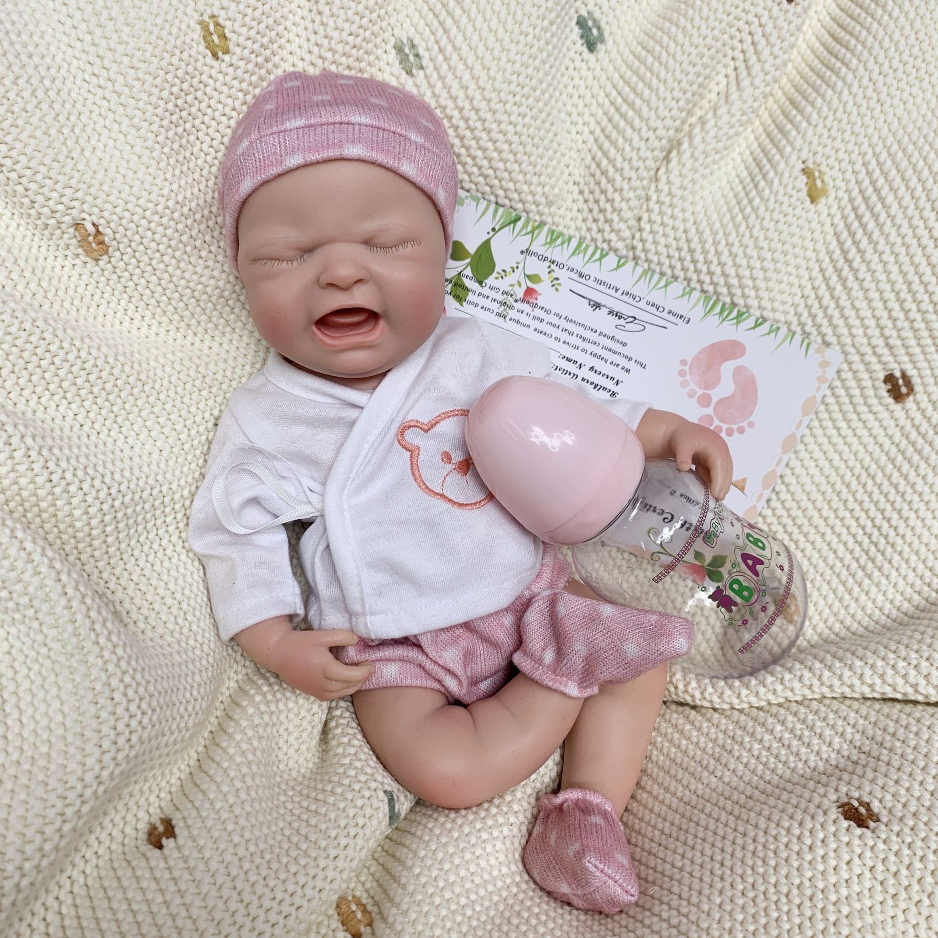 Poupée reborn en silicone de 33 cm (13 pouces) qui pleure Poupée reborn réaliste en silicone de 33 cm (13 pouces) qui pleure, avec biberon, vêtements doux et chapeau rose.