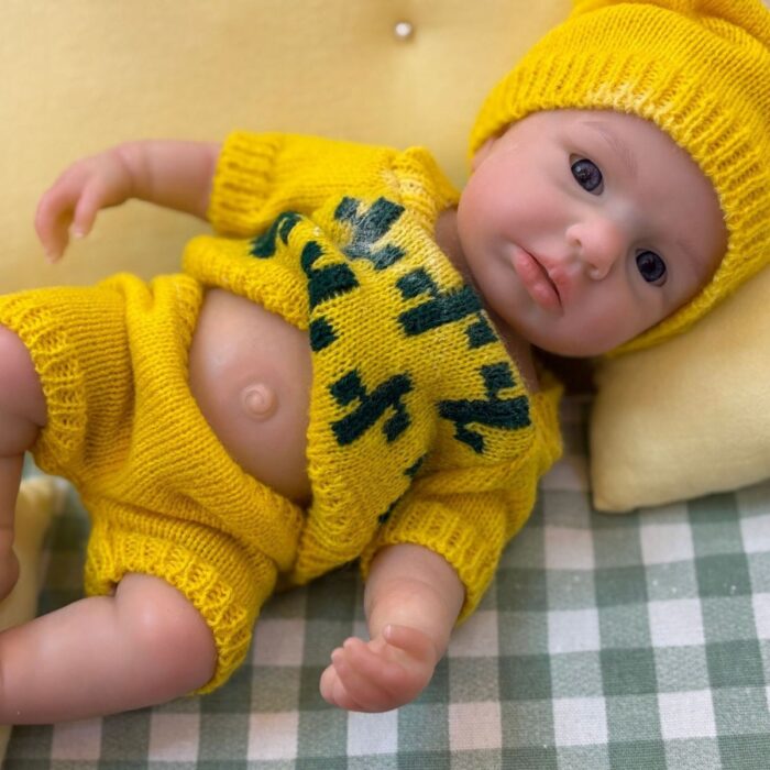 Poupée reborn réaliste en silicone, vêtue de vêtements jaunes, aux traits réalistes, pour collectionneurs et enfants.