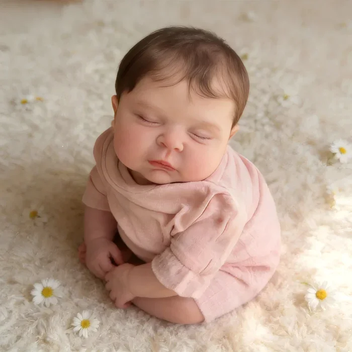 Realistic baby reborn doll sleeping on soft surface with daisies, lifelike details.