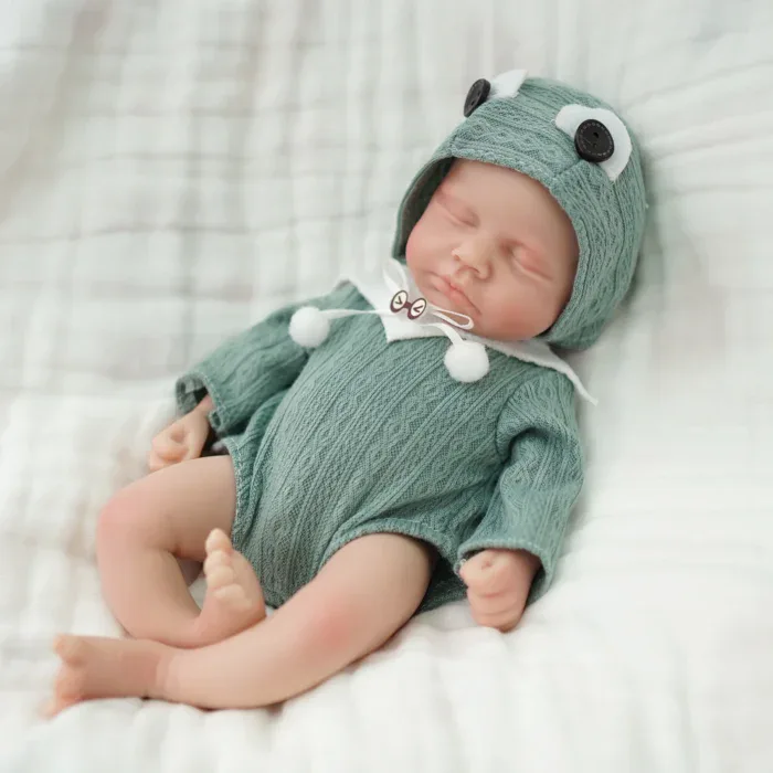 Poupée micro prématurée réaliste en silicone avec chapeau et tenue verts.