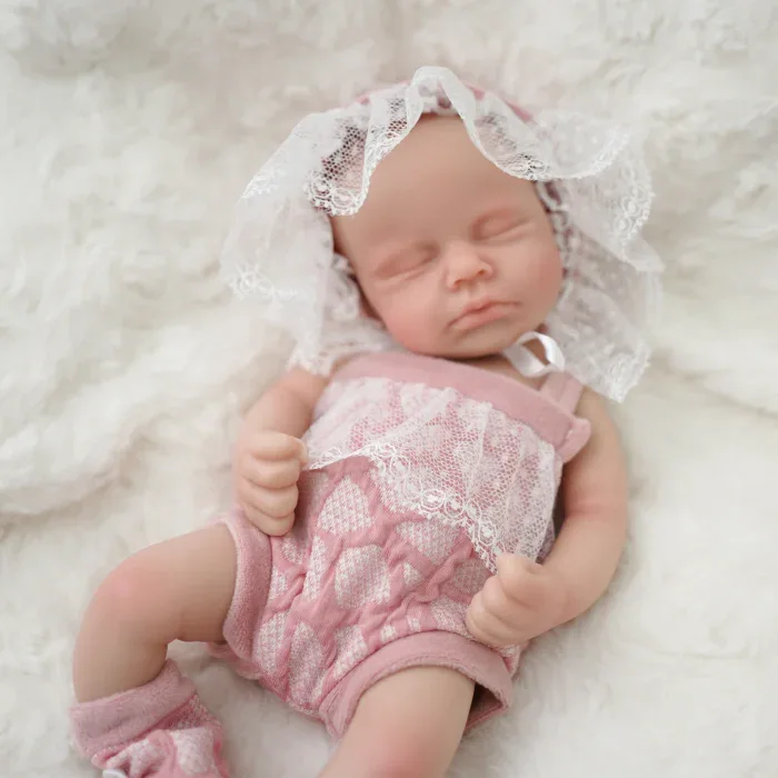 Poupée prématurée réaliste en silicone avec tenue rose et bonnet en dentelle.