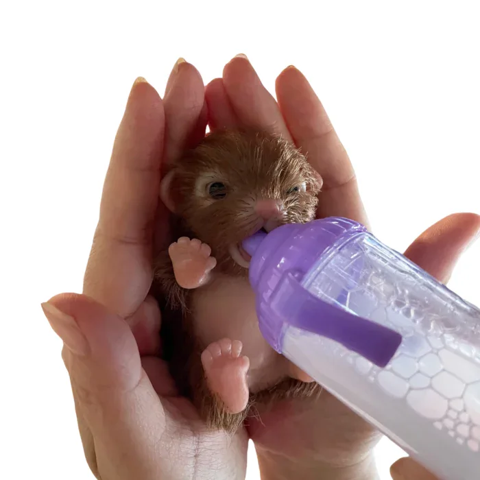 Small silicone reborn puppy being fed with a bottle in a person's hand.