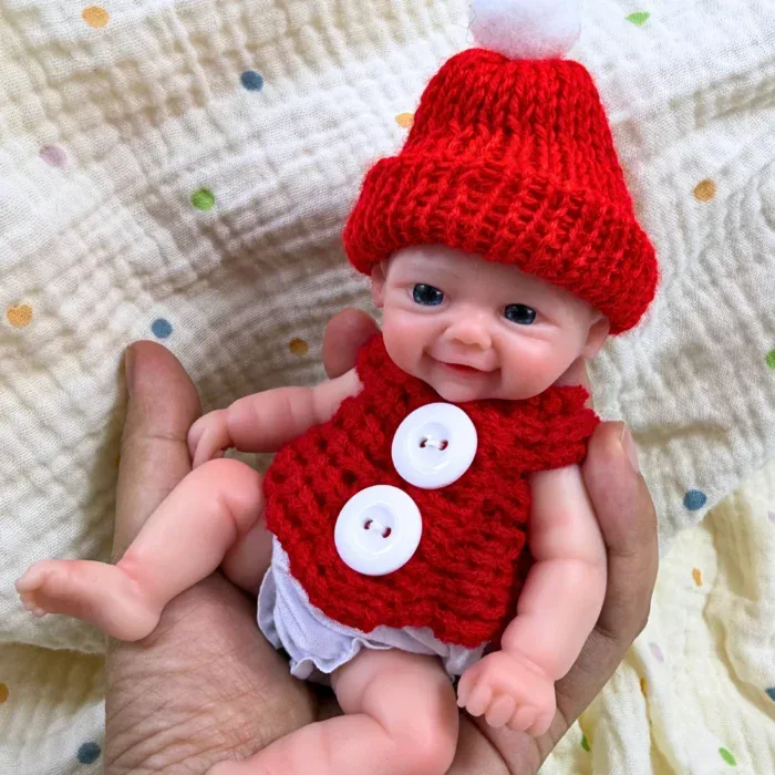 Adorável mini boneca reborn de silicone, menina, vestida com uma roupa e chapéu vermelhos festivos.
