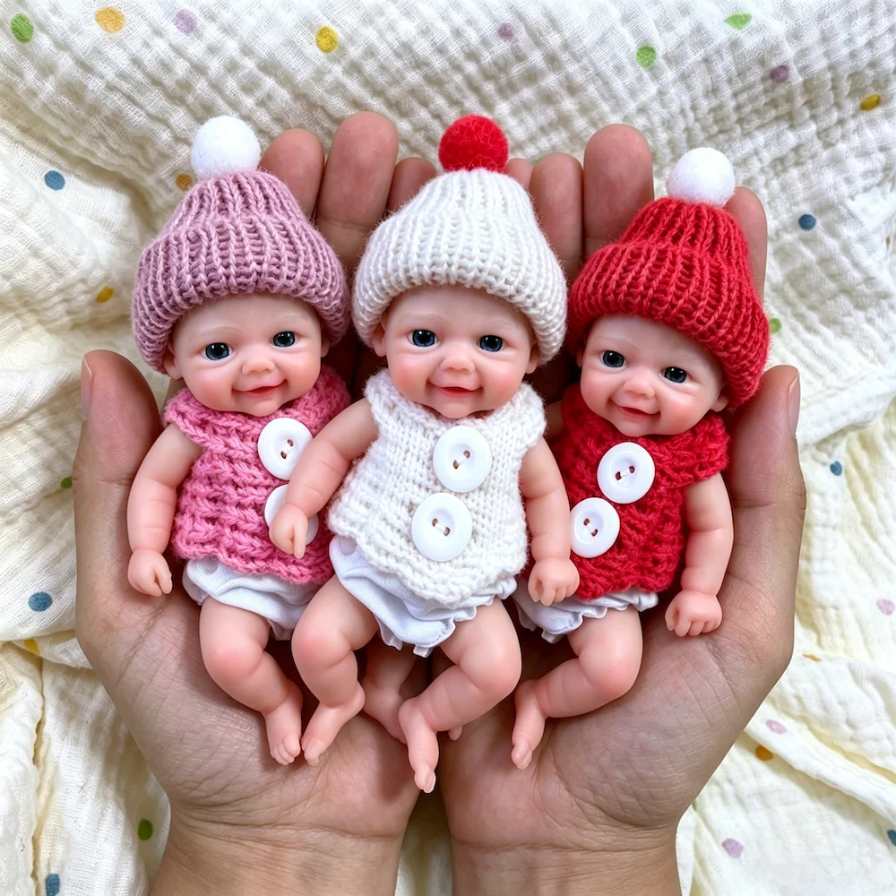 Conjunto de Mini Bonecas Bebê Reborn de Silicone Três minúsculas bonecas reborn de silicone com gorros e roupinhas de tricô coloridas.