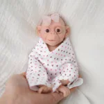 Adorable 7-inch silicone baby doll with wide eyes and pink bow.