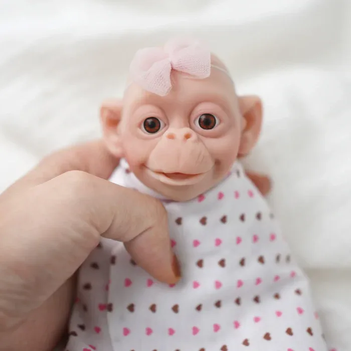 Adorable 7-inch silicone reborn monkey doll with wide eyes and pink bow.
