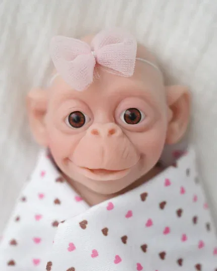 Adorable wide-eyed baby girl silicone reborn doll with pink bow and heart-patterned blanket.