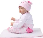 Реалистична кукла момиченце в розова шапка и пижама, спяща спокойно.