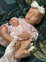 Bebê prematuro realista adormecido, feito de silicone, com faixa de laço na cabeça.