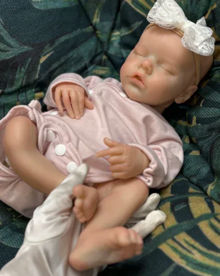 Bebê prematuro realista adormecido, feito de silicone, com faixa de laço na cabeça.