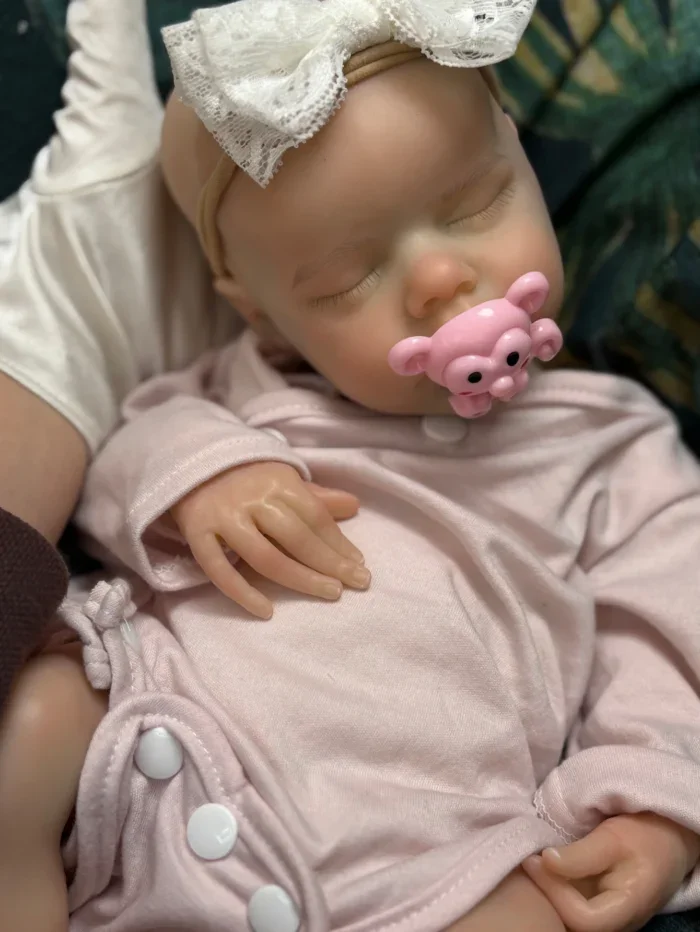 Bebê prematuro realista adormecido, feito de silicone, com chupeta e faixa de cabeça.