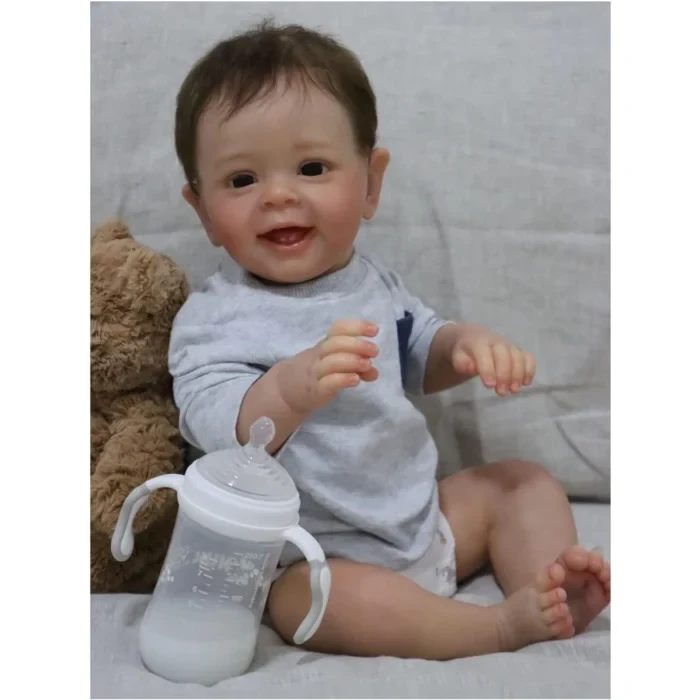 Adorable laughing toddler boy with a sippy cup, sitting on a couch.