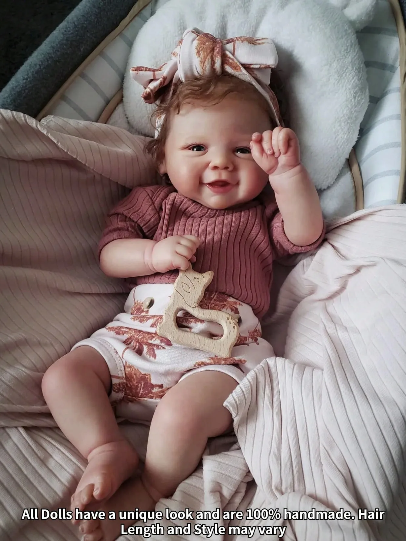 Reborn bábika Hazel s úsmevom a dievčatkom Rozkošné usmiate dievčatko s mašľou vo vlasoch, ležiace na útulnej posteli.