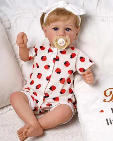 Poupée bébé réaliste aux yeux bleus et aux cheveux blonds, vêtue d'une tenue à imprimé fraise.