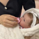 Poupée réaliste aux yeux bleus nourrie au biberon rose.