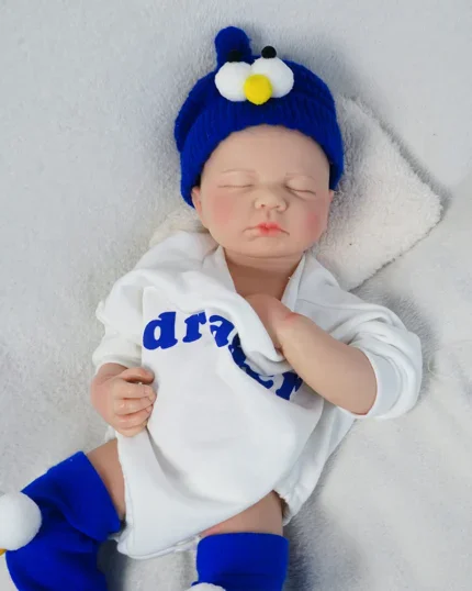 Realistisk drengedukke med blå hat og outfit til reborn-dukkekollektionen.