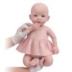 Poupée bébé réaliste en silicone avec robe rose, traits réalistes et finitions soignées.