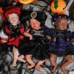 Trois poupées reborn déguisées sur le thème d'Halloween, sur un tissu noir.