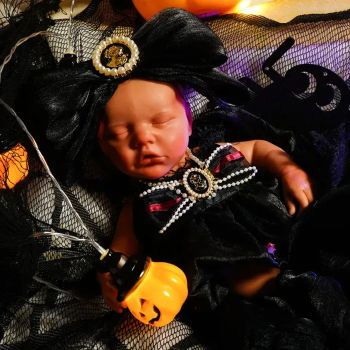 Poupée reborn réaliste sur le thème d'Halloween, avec robe noire et accessoire citrouille.