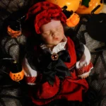 Poupée bébé fille endormie en costume d'Halloween avec des citrouilles et des lumières.
