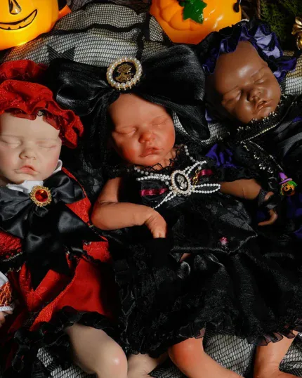 Three Halloween-themed reborn baby dolls in costumes with pumpkins and decorations.