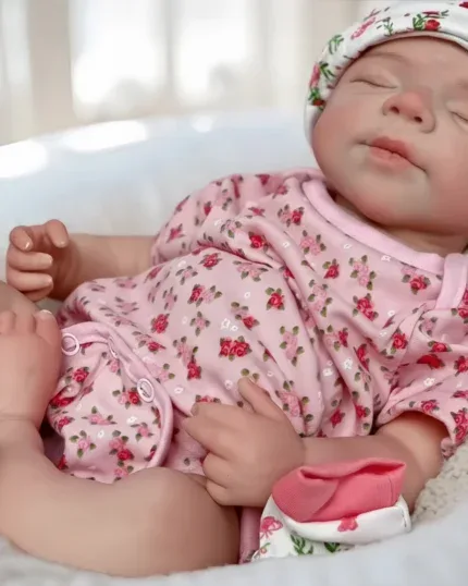 Sleeping baby girl doll in pink floral outfit with hat, realistic silicone skin.
