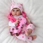 Realistische Babypuppe mit rosa Giraffen-Plüschtier und rosa gepunktetem Outfit.
