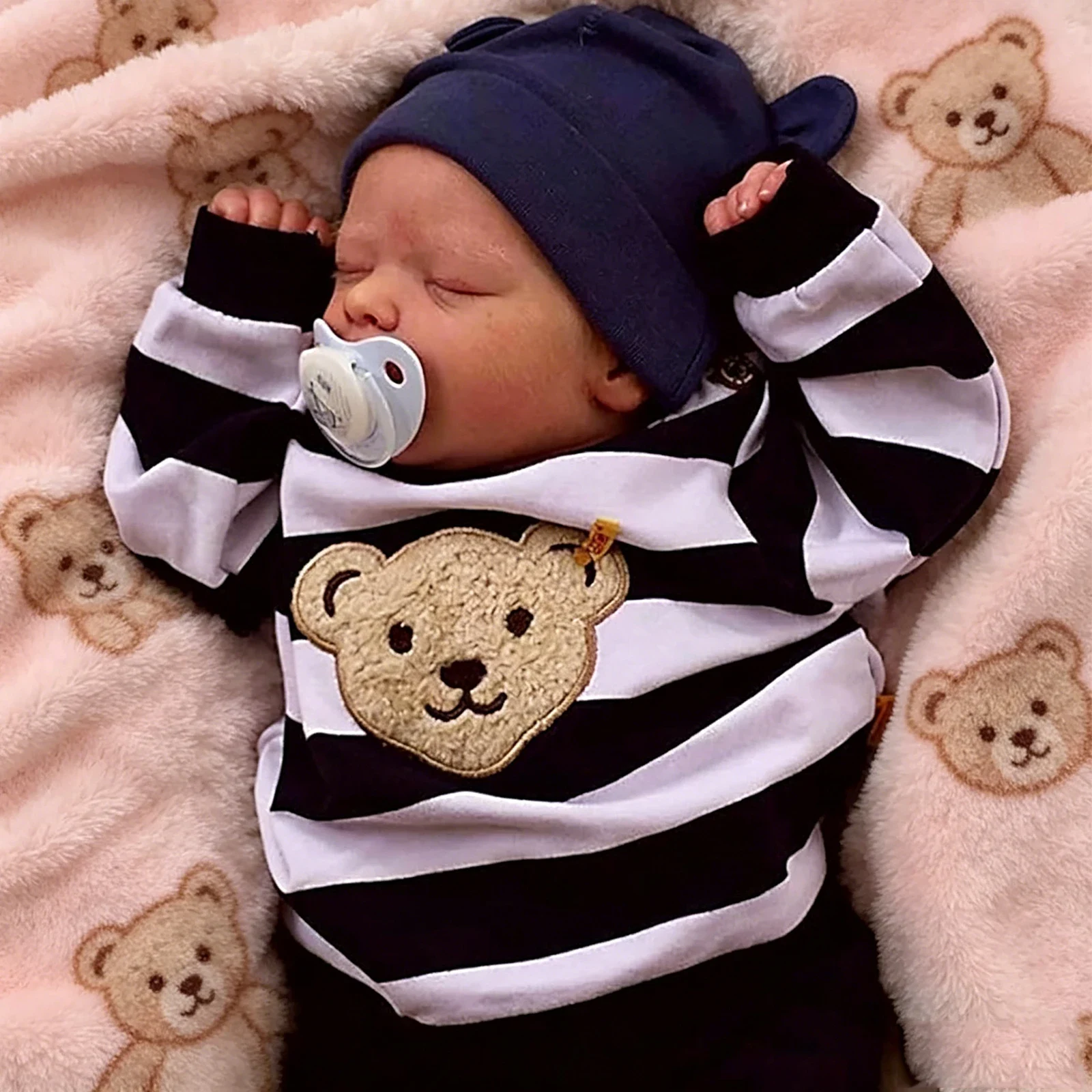 Realistische Reborn-Babypuppe im gestreiften Outfit Realistische Babypuppe mit Schnuller in gestreifter Kleidung und marineblauem Hut.