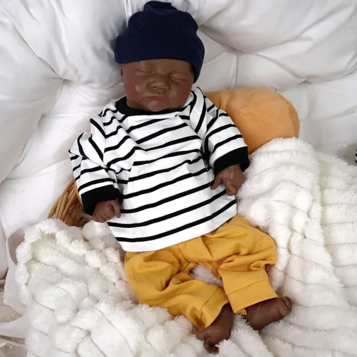 Poupée reborn réaliste de petit garçon noir avec chemise rayée et pantalon jaune.
